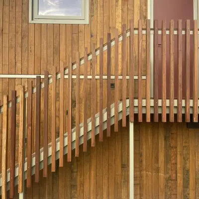 Wooden exterior wall with a vertical slat fence treated with ACQ and a ramp in front, featuring a window and door above.